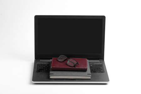 Modern workspace with laptop keyboard, notebook, spectacles on whiteの写真素材