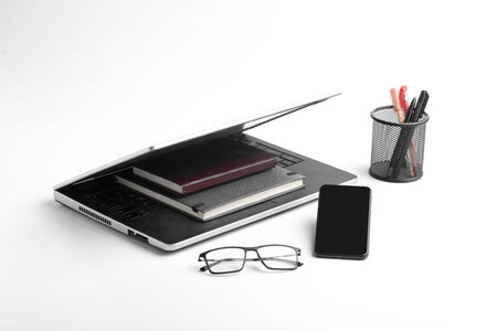Modern workspace with laptop keyboard, notebook, spectacles on white