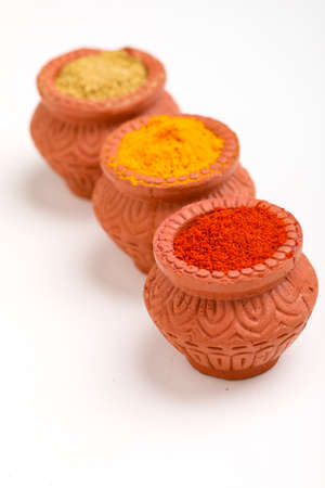 Red chilli powder,turmeric powder and coriander powder in clay bowl with other spices.の写真素材