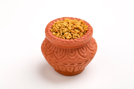 Dry seeds of fenugreek in a clay bowl isolated on white background.の写真素材