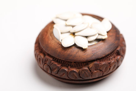 Heap of pumpkin seeds in bowl on white backgroundの写真素材
