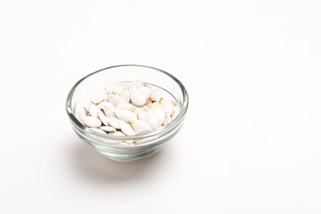 Heap of pumpkin seeds in bowl on white backgroundの写真素材