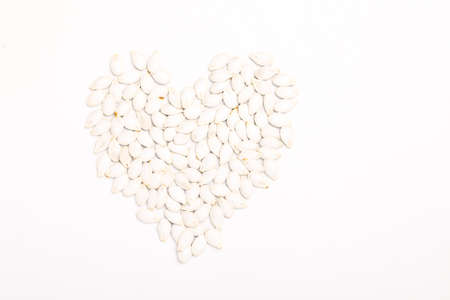 heart shape of pumpkin seeds isolated on white backgroundの写真素材