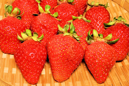 Strawberries in a basket on a bamboo tablecloth, closeup of photoの写真素材