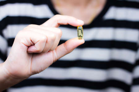 Medicine pills or capsules in hand, palm or fingers. Drug prescription for treatment medication. Pharmaceutical medicament, cure in container for health. Antibiotic, painkiller closeup.のeditorial素材