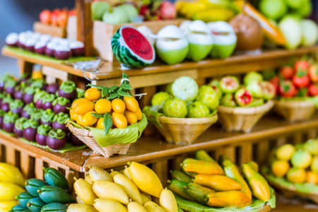 close up Miniature clay figurine Thailand's floating market,Miniature boat carrying tropical fruit on wood backgroundの写真素材