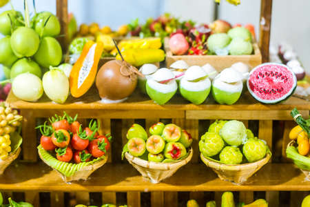 close up Miniature clay figurine Thailand's floating market,Miniature boat carrying tropical fruit on wood backgroundの写真素材