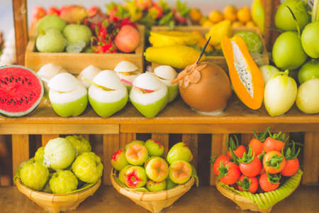close up Miniature clay figurine Thailand's floating market,Miniature boat carrying tropical fruit on wood backgroundの写真素材