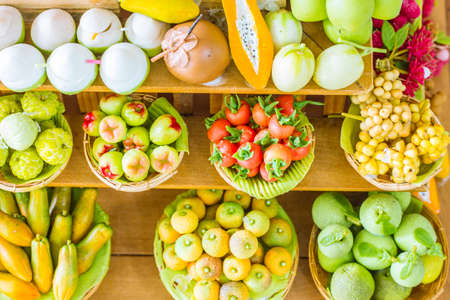 close up Miniature clay figurine Thailand's floating market,Miniature boat carrying tropical fruit on wood backgroundの写真素材