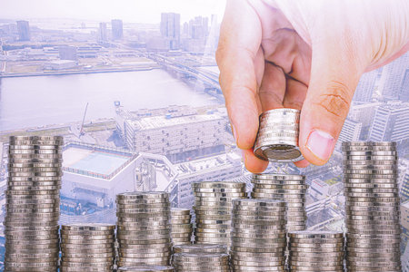 Exposure of Finance and Saving money banking concept,Hope of investor concept,Male hand putting money coin like stack growing business. background the cityの写真素材