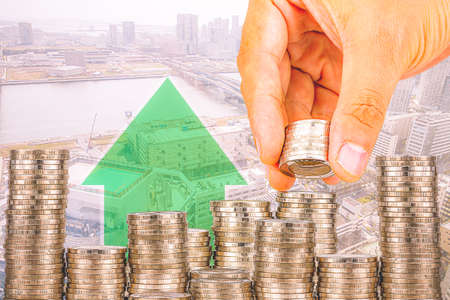 Exposure of Finance and Saving money banking concept,Hope of investor concept,Male hand putting money coin like stack growing business. background the cityの写真素材