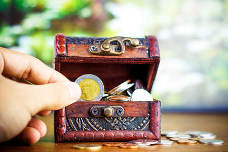 Saving money concept preset putting money coin stack growing business on bright light glowing bokeh background, business finance wealth and success concept.の写真素材