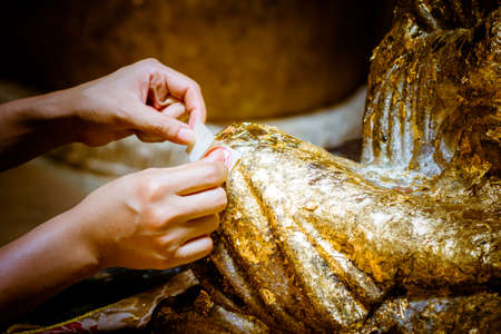 Put gold leaf onto (The Buddha image/ The Buddha statue)/ to gild. Which I use to worship the buddha imageの写真素材