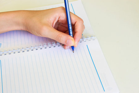 pen in left hand writing on the notebook