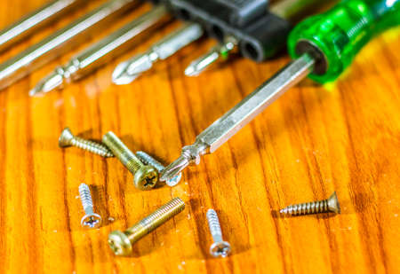 Close-up of screwdriver and small screw on tip set head screw driver and screw on wood backgroundの写真素材