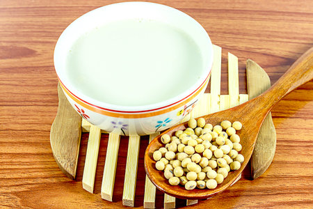 Soy milk on wooden background with soybeans or soya beans placed on side, selective focus,Healthy foodの写真素材