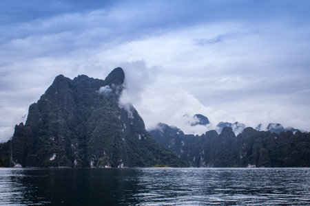 Landscape with mountains trees and mist  and a lake  in front,Evening after heavy rainy day.