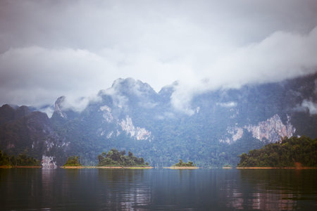 Landscape with mountains trees and mist  and a lake  in front,Evening after heavy rainy day.