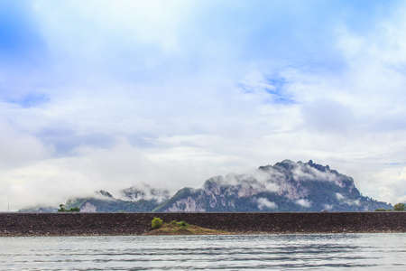 Beautiful landscape with background mountains trees and mist and a river sky and natural attractions in front at dam Thailand. Evening after heavy rainy day.Concept image for nature,scenery,travelの写真素材