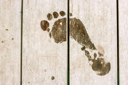 Wet human footprints on dark wooden plank floor. Walk from beach to hotel or home. Abstract backgrounds and wallpapers. Holidays and vacations in summer.の写真素材