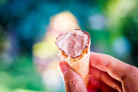 Young beautiful woman hands holding melting ice cream in hands on summer light nature background,Happy woman eating ice creamの写真素材