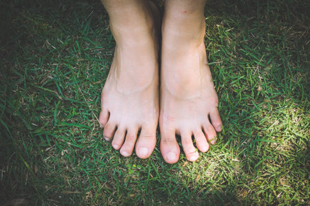 bare feet and hands with creative teens manicure and pedicure on the green grass lawn...