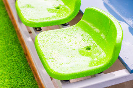Close up chair green,green plastic stadium seats arranged in a row. The image has been made before the beginning of a tennis game,Blurred background of crowd of people at the stadiumの写真素材