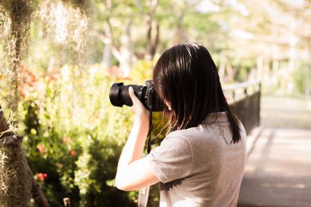 woman photographer taking outdoor portraits with prime lens at sunset, during a sunny dayの写真素材