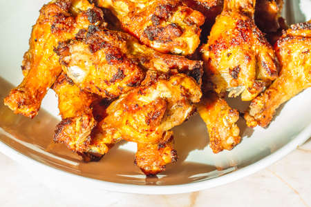 Grilled chicken drumsticks fried crispy marinated with honey is served in a flat white dish on a white background , Asian flavors and style, close-up の写真素材