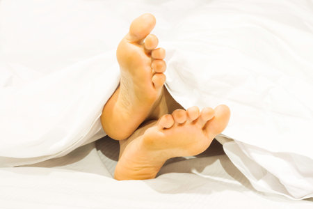 Closeup two feet on the bed a white background with sleeping at home relaxing in holidays.