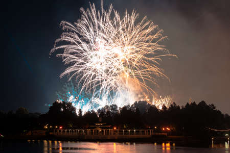 Fireworks blooming in the sky reflected in the water of a lagoon.の写真素材