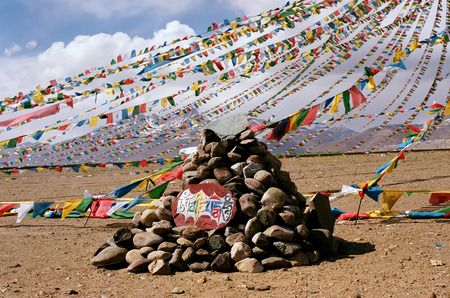 Prayer flags and mantra of Compassions Bodhisattva "Om Mani Padme Hum", which translates as "Oh treasure inside the lotus flower", on the stone.の写真素材