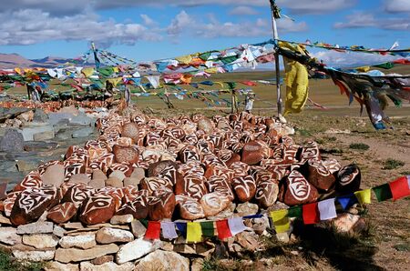Stones with Buddhist mantras and prayer flagsの写真素材