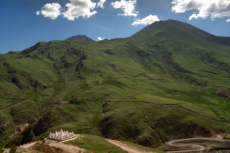 Green hills and white Stupas near Buddhist cave monastery Druk Yerpa in vicinity of Lhasa, Tibet.の写真素材