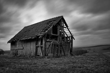 old spooky abandoned barn with clouds in the backgroundの写真素材