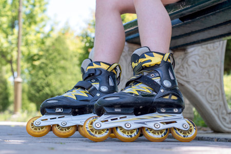 A teenage girl sits in a park wearing roller skates, getting ready to go skating. Concept is to...