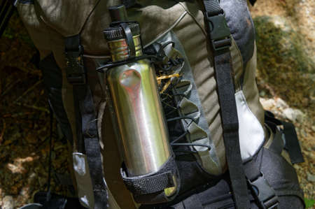 A stainless steel drink bottle on the back of a hiking backpack.の写真素材