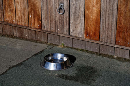 A stainless steel water bowl and tie up ring outside a restaurantの写真素材
