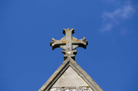 A cross sits on top of a church against a blue skyの写真素材