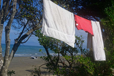 Towels and a red t-shirt are hanging on a line to dry at a sea side campgroundの写真素材