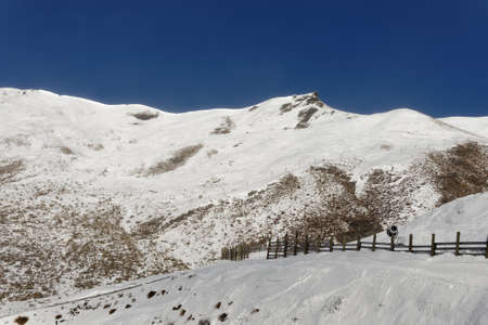 Snow mountains against a sunny, blue skyの写真素材