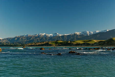 A beautiful blue green sea sets off snow capped mountains in Kaikoura, New Zealandの写真素材