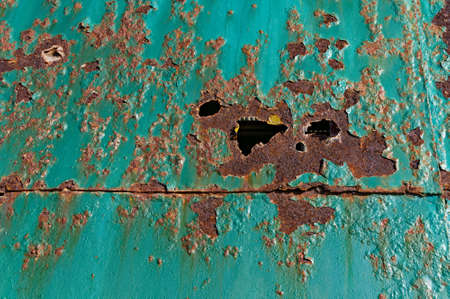 Rust never sleeps, holes formed by sea air corrosion on a metal doorの写真素材