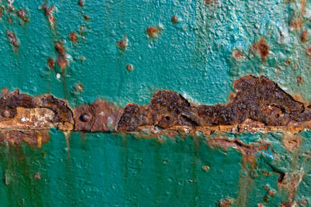 Rust is eating away at the teal paint on a metal doorの写真素材