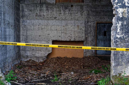 Asbestos dust hazard yellow warning tape is strung across the entrance to a buildingの写真素材