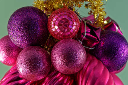 Purple and red Christmas decorations with gold tinsel on a green backgroundの写真素材