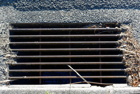 Road drainage, a grilled stormwater drain with a stick in it.