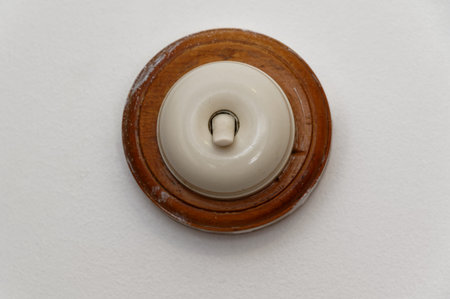 A round light switch is backed by wood and in the on position