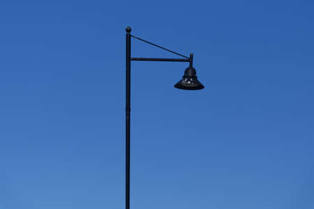 A decorative black iron looking lamppost with lamp shade, there is bird poo on the shadeの写真素材