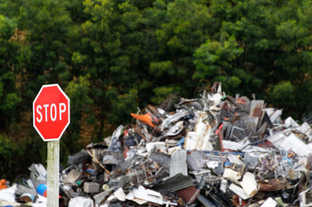 A red stop sign sends a message as it is positioned in front of a large pile of metal rubbish